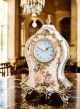 Tischuhr aus edler Keramik, mit eleganten floralen und goldenen Details, handgefertigt.
